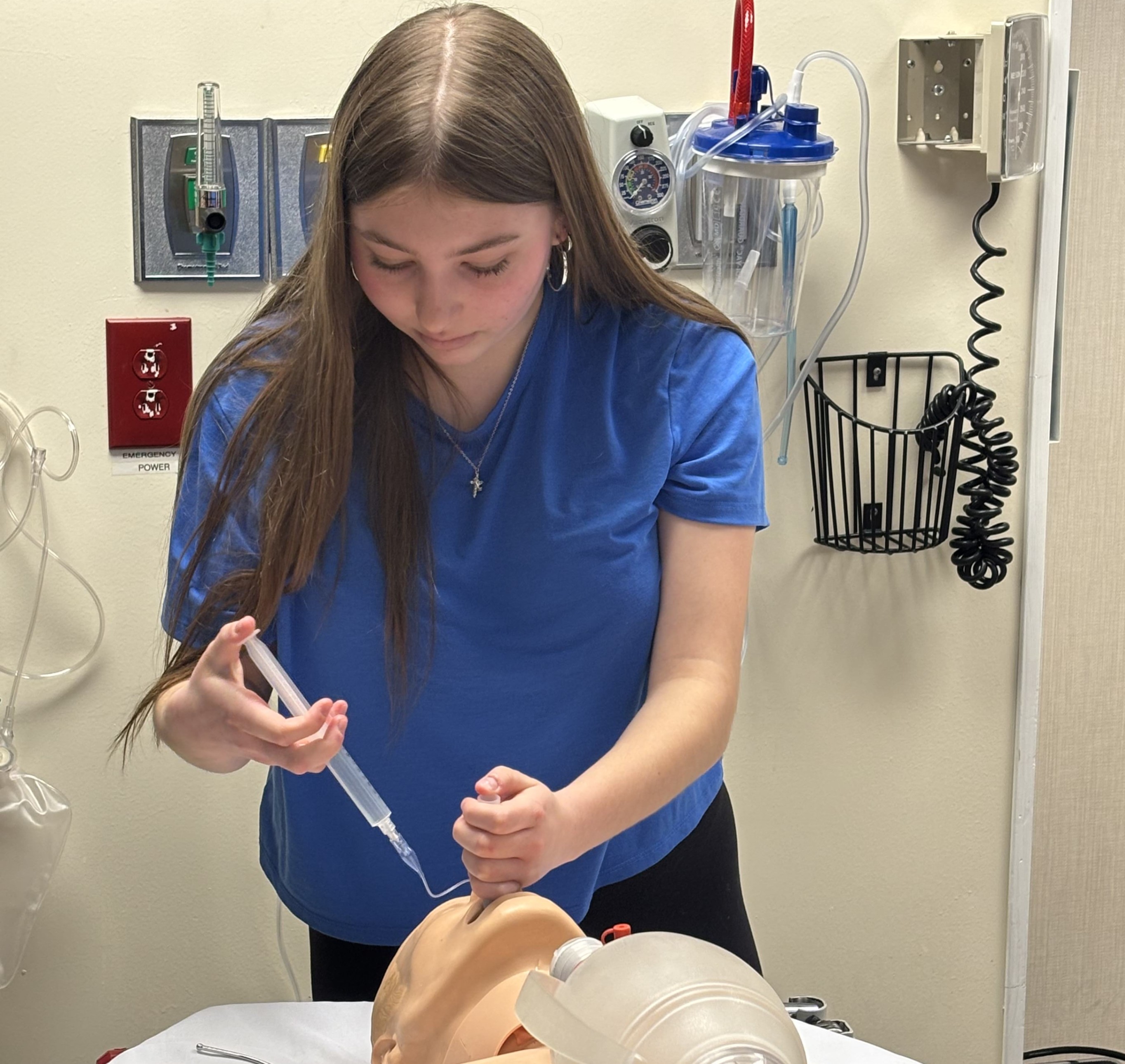 Corrine Siar uses medical instruments to intubate a training dummy.