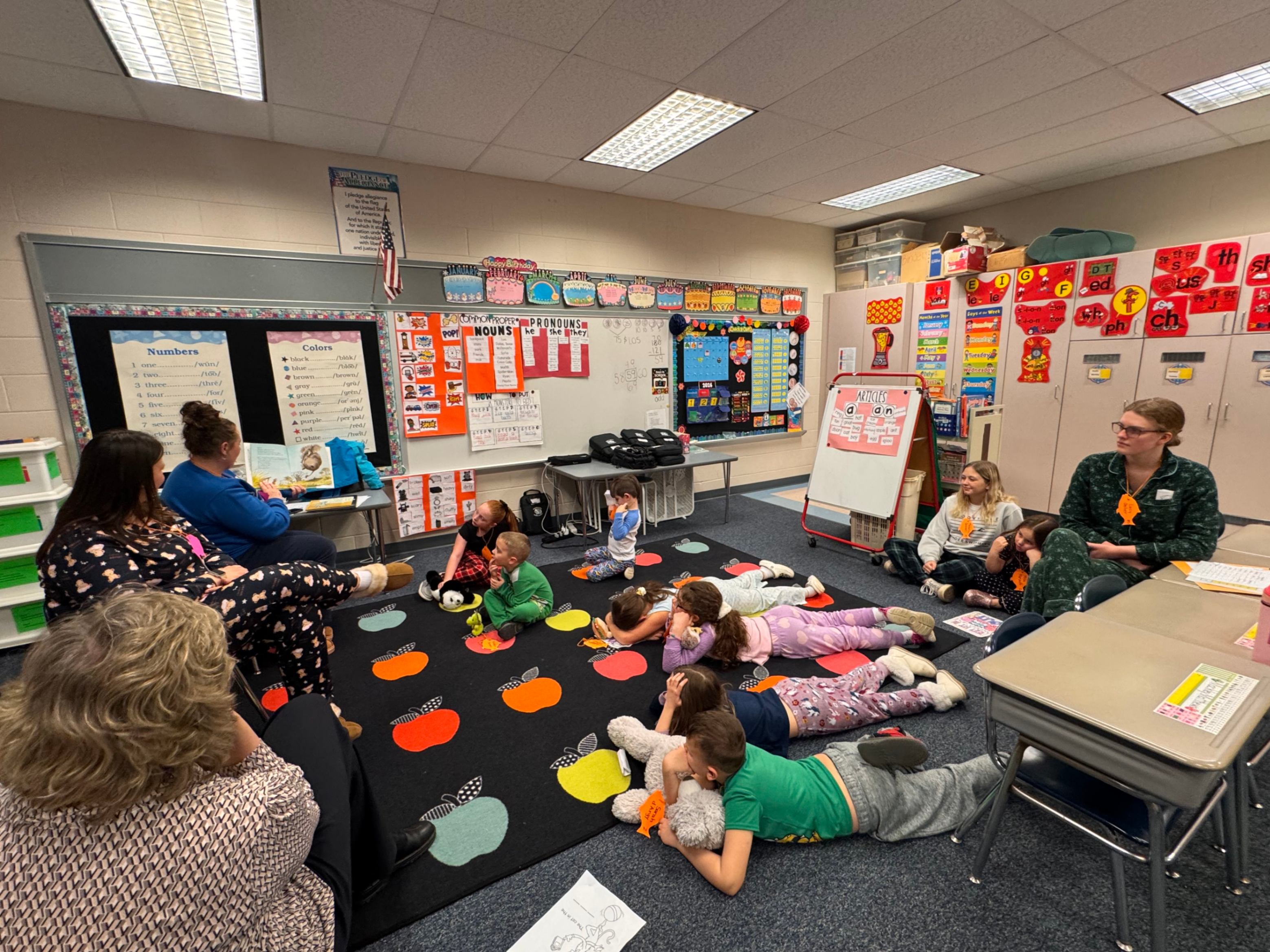 Students and other participants listen to a story being read by a volunteer during bedtime story night recently at Pinecreek Elementary.