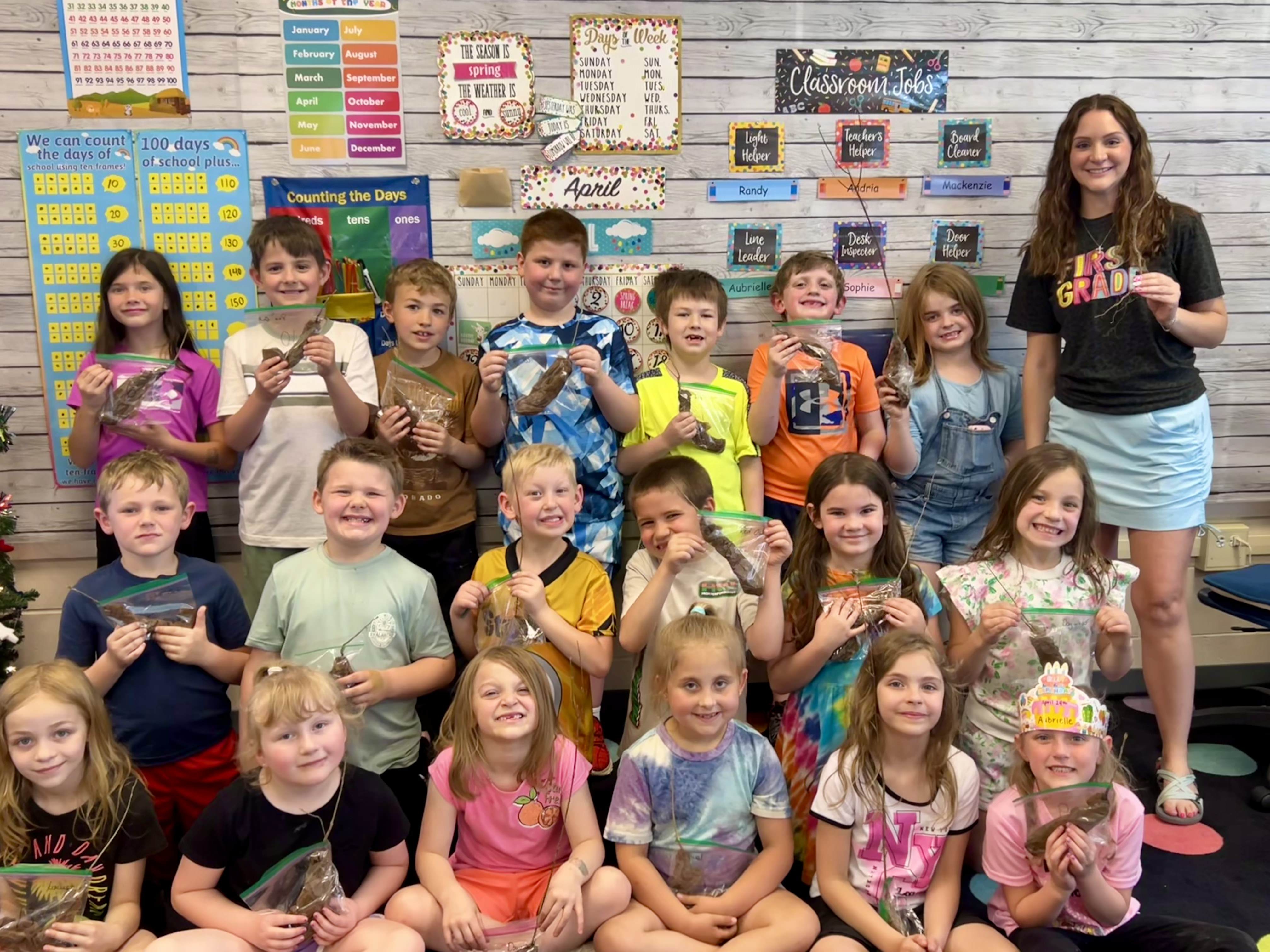 Pinecreek teacher Maggie Brown and her students pose for a group photo while holding their seedlings.