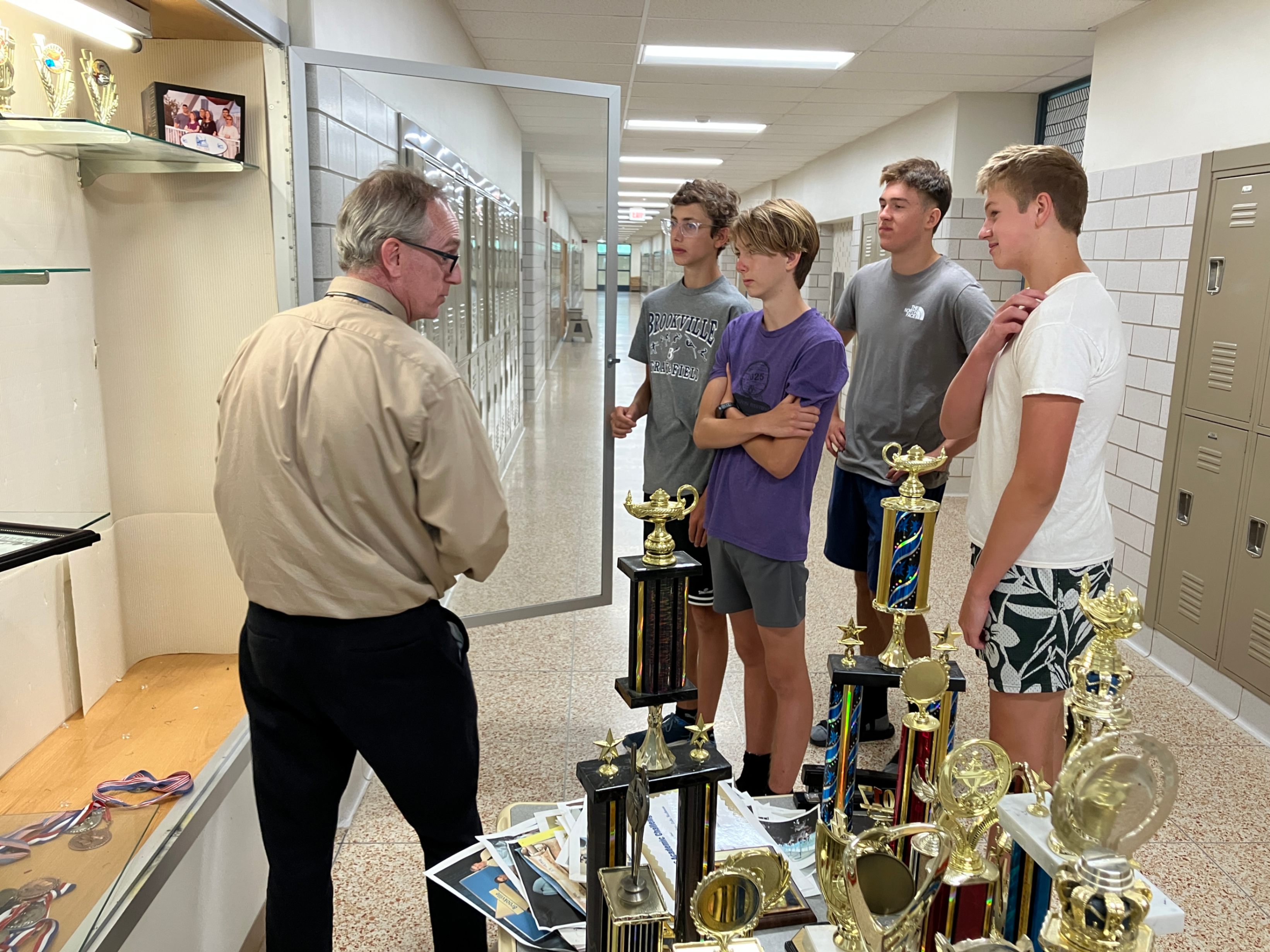 Mr. Deemer and NHS students reorganizing a trophy case.