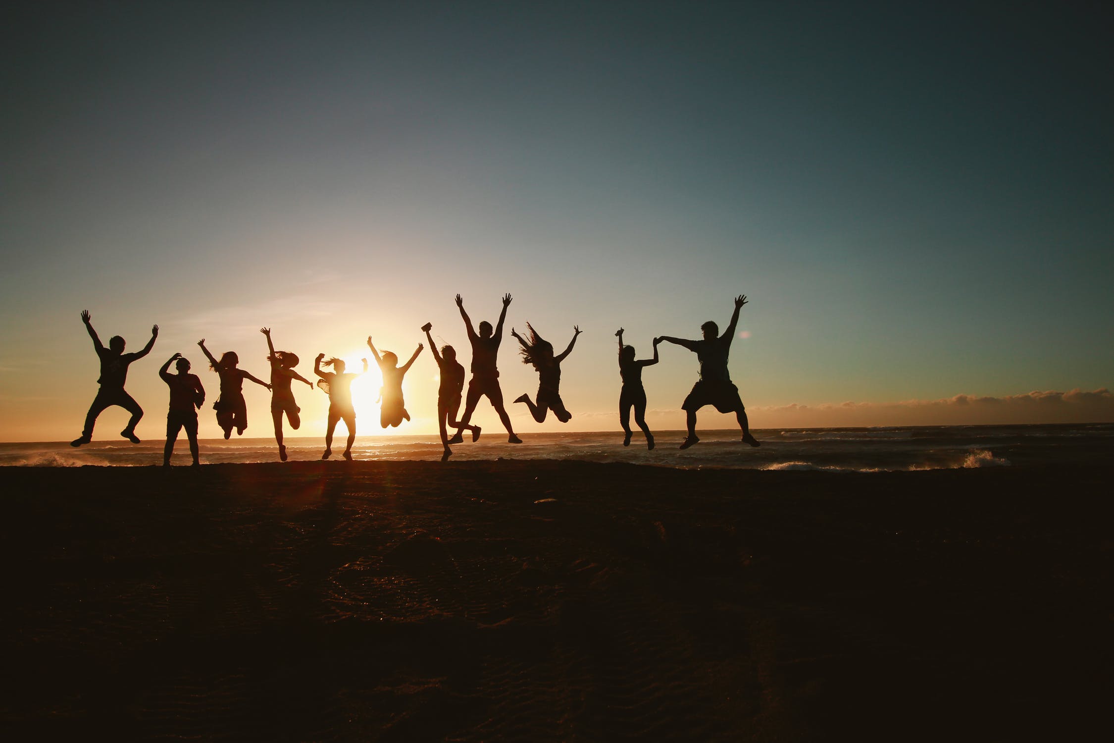 A group of people standing in line silhouetted by setting sun