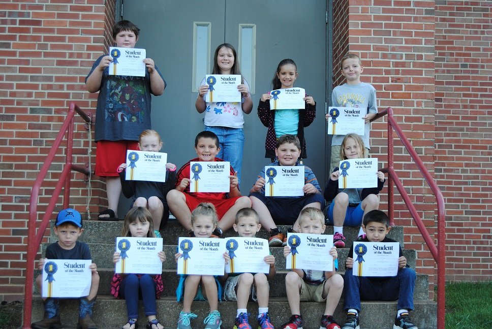 Students pose with their "Student of the Month" awards on school steps.