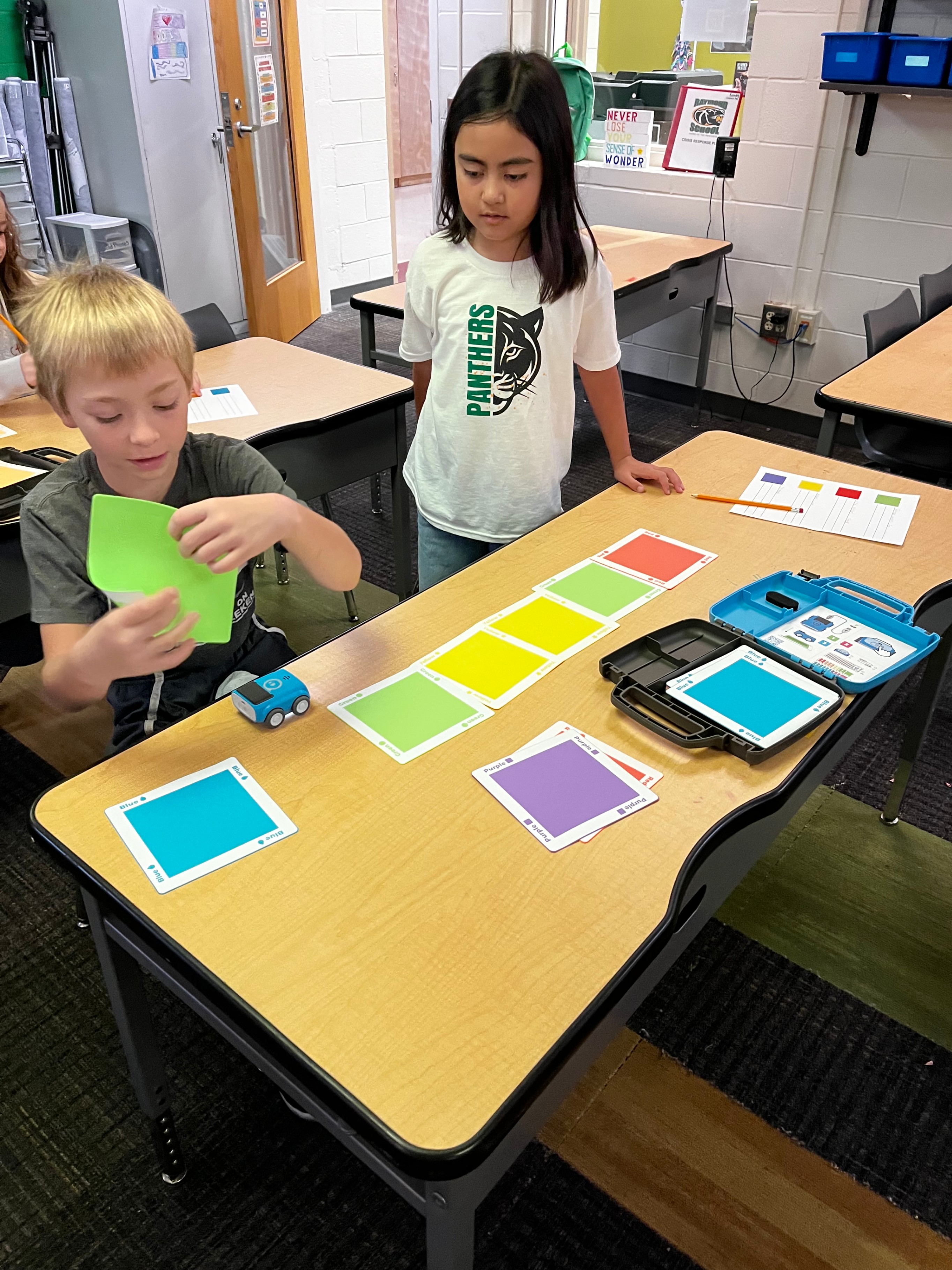 Two students stand around color tiles