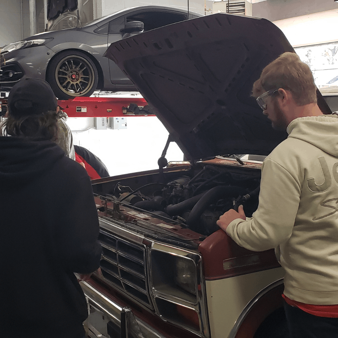 Students touring GSCC Manufacturing Center Automotive dept (car hood up)