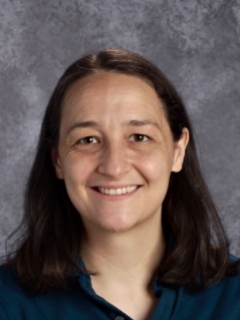 Headshot of a woman with shoulder length brown hair, smiling sincerely at the camera.