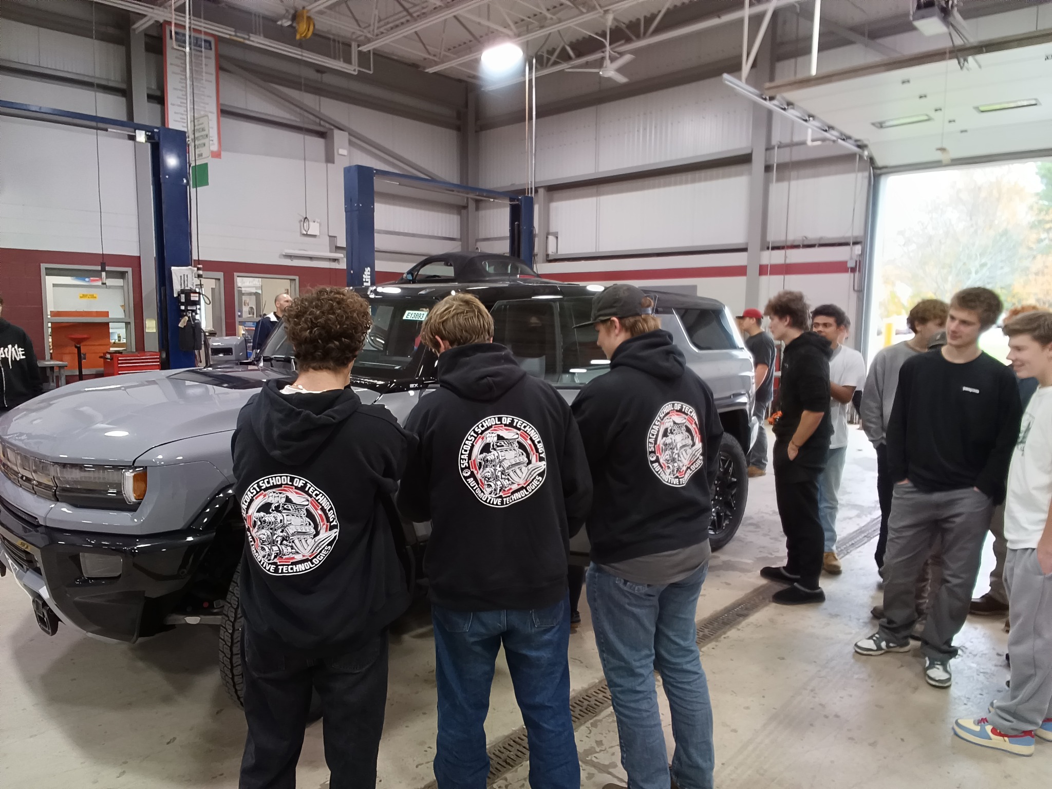 A student working under a vehicle that is up on a lift. 