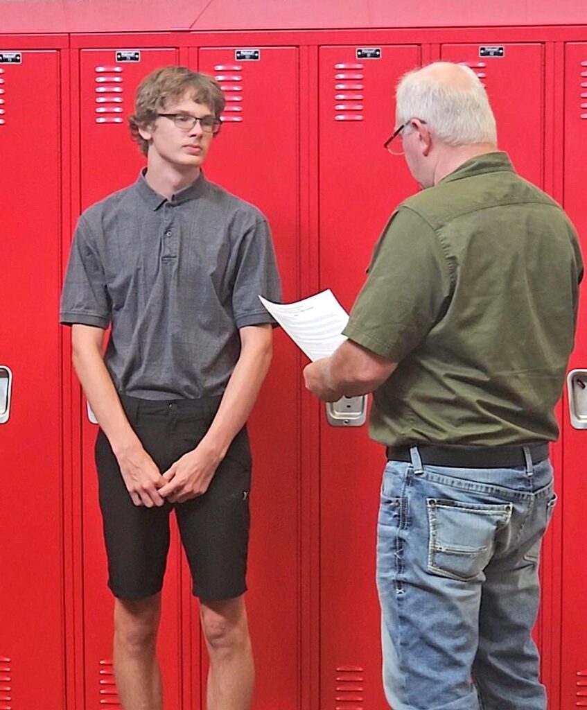Rod Zobel administering the oath of office to student board member Kinsley Even.