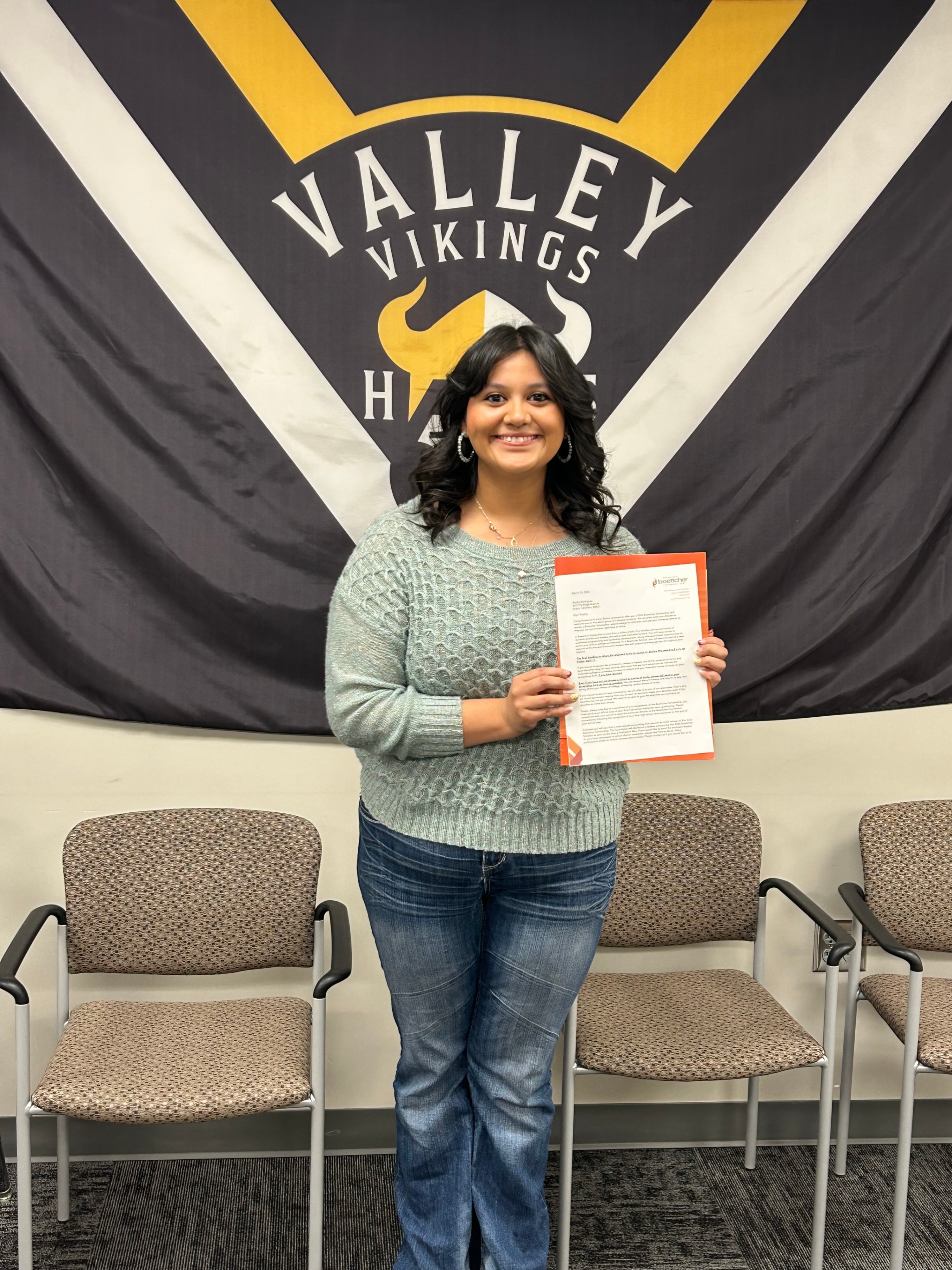 Senior Sophia Rodriquez holding a certificate with a  Valley Vikings Flag behind her. 