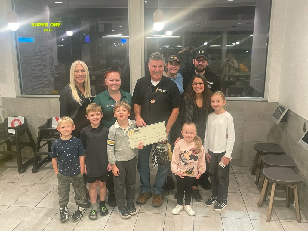 Staff, workers, and students stand with large check from killian management