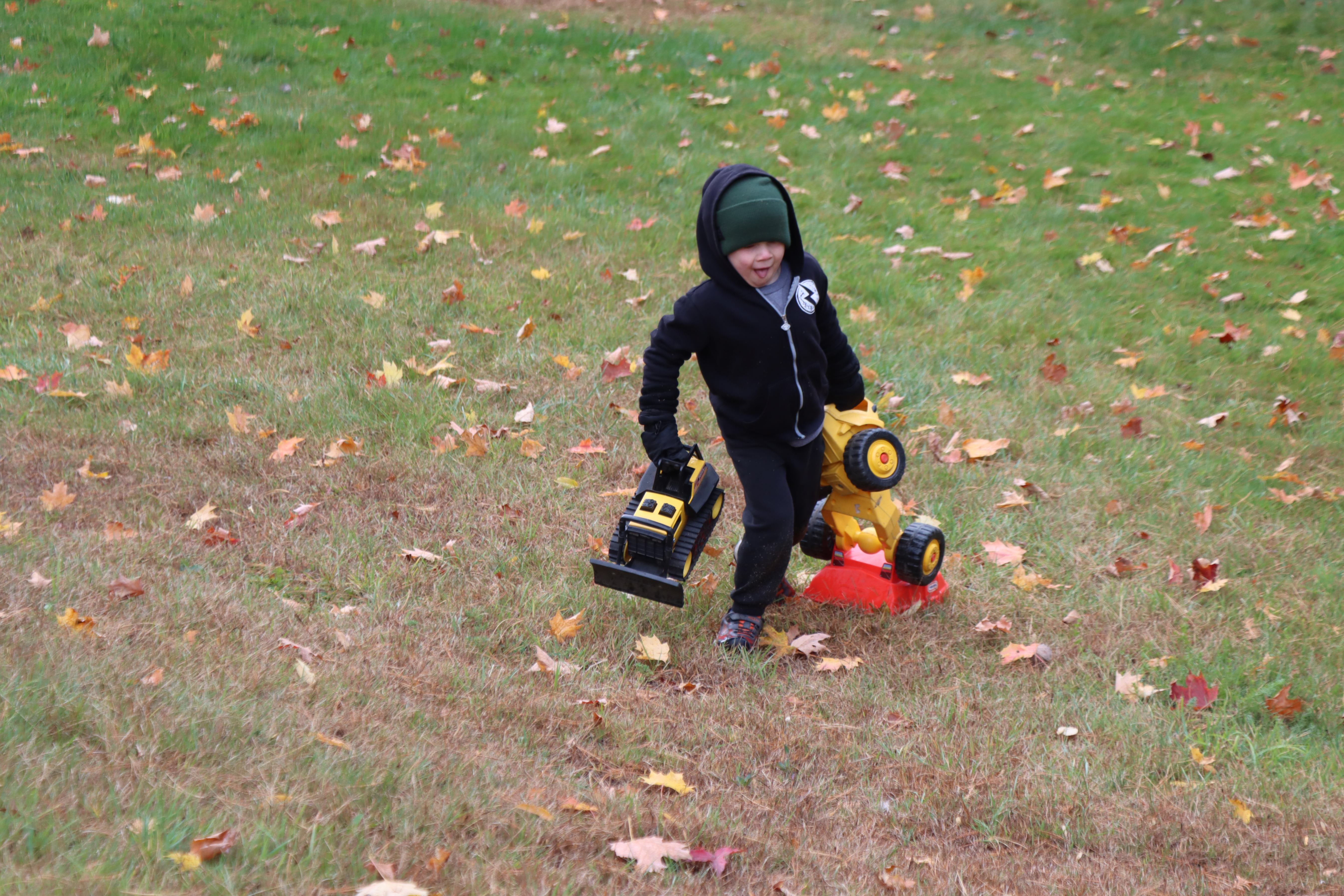 student carrying toy trucks during outdoor time