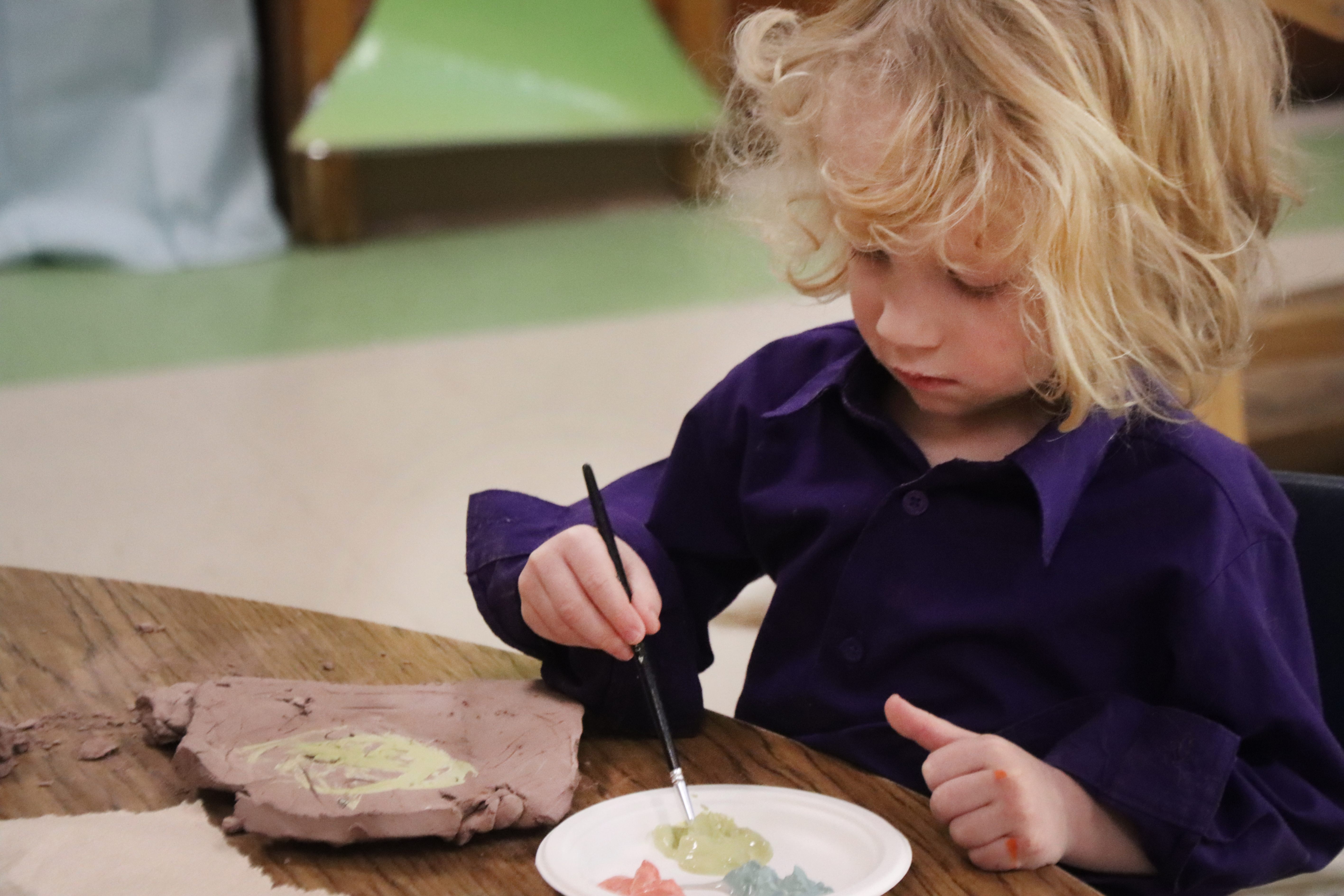 preschool student painting on clay