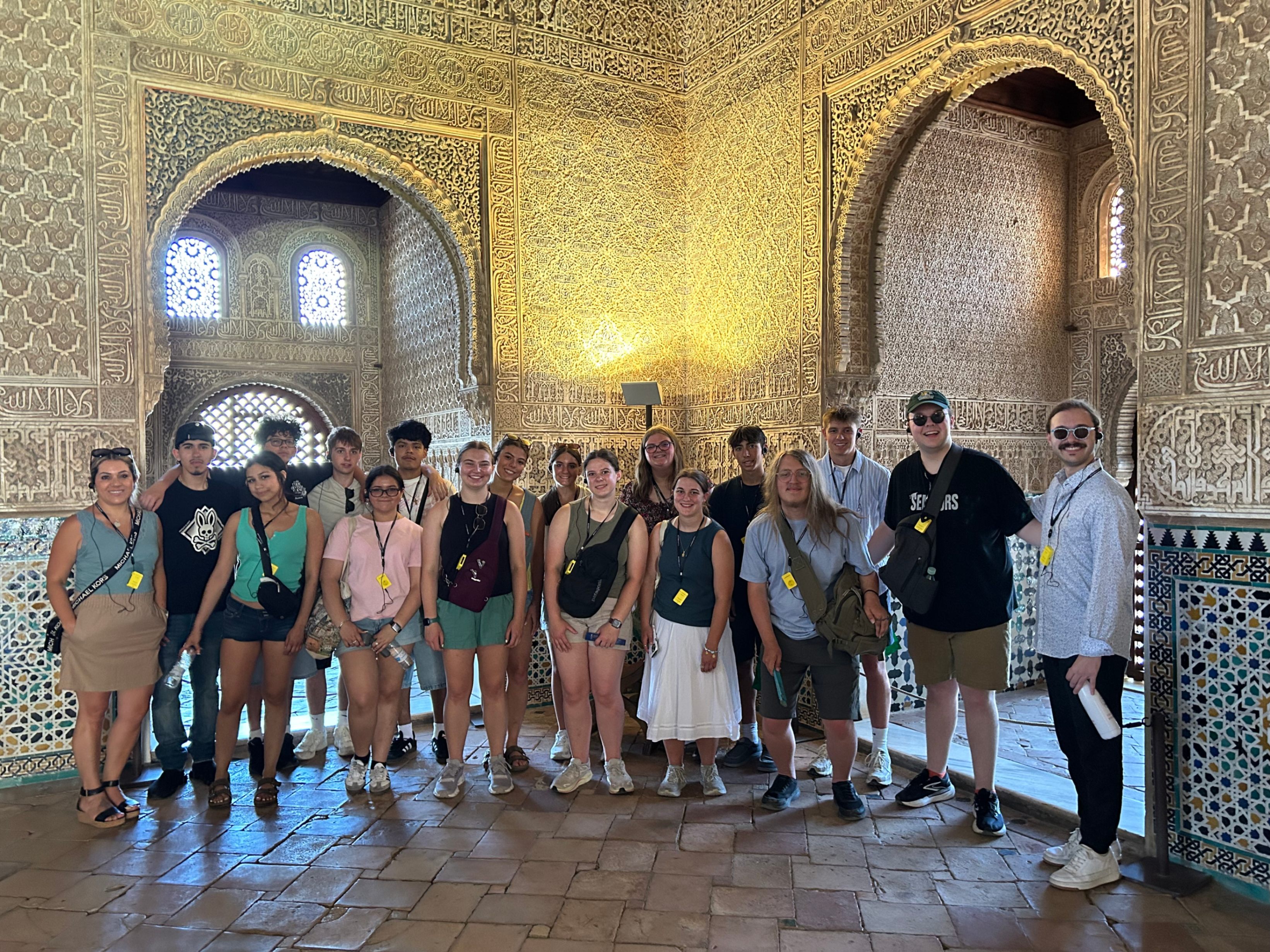 A group of students standing together inside a historic room at the Alhambra, surrounded by incredibly detailed carved plaster walls and arches.