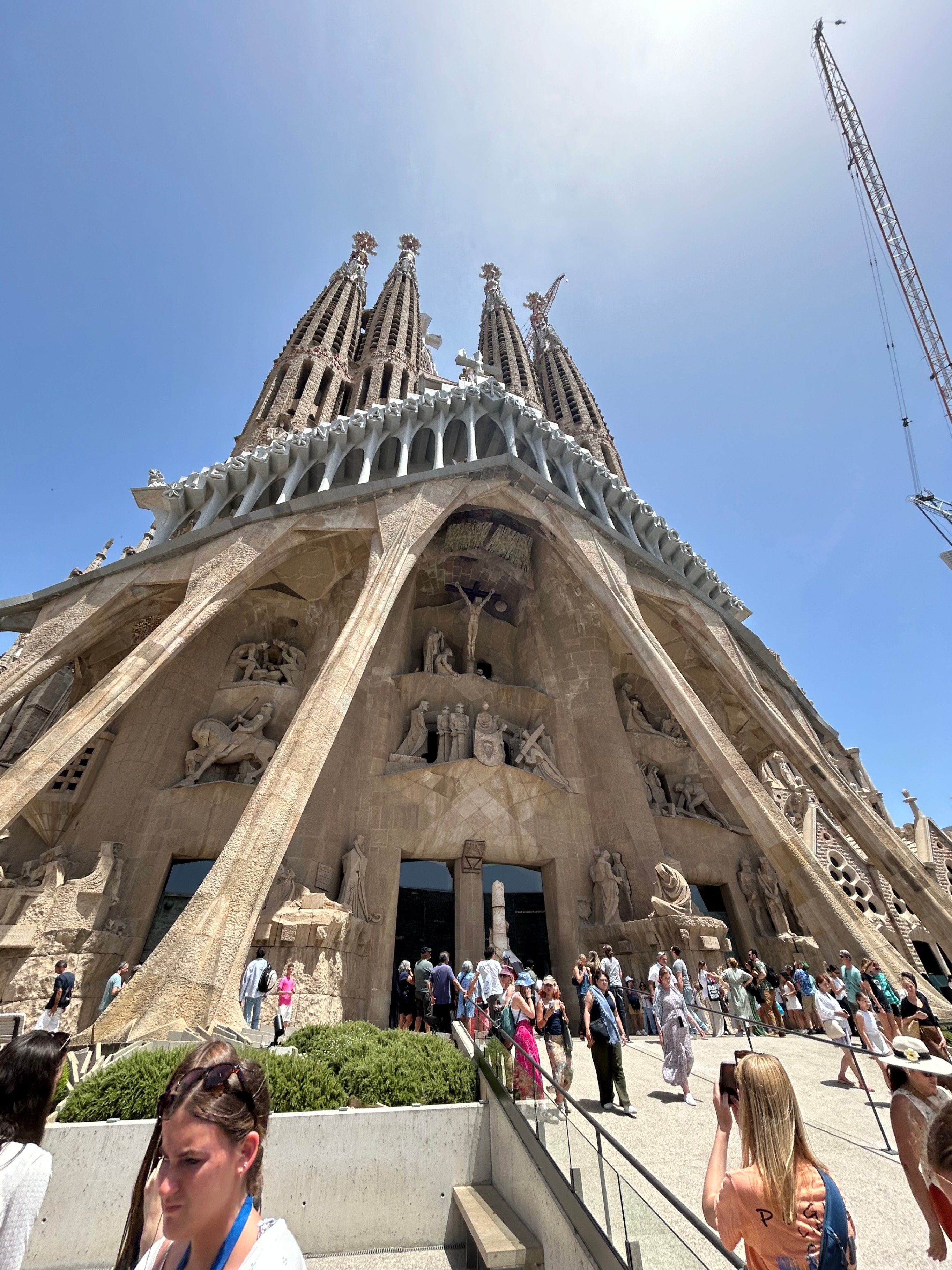 Looking up at the dramatic stone carvings, angular statues, and towering spires of the Passion Façade at the Sagrada Família.