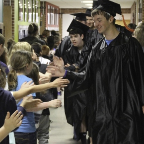 young and old students high fiving while passing in the hallway