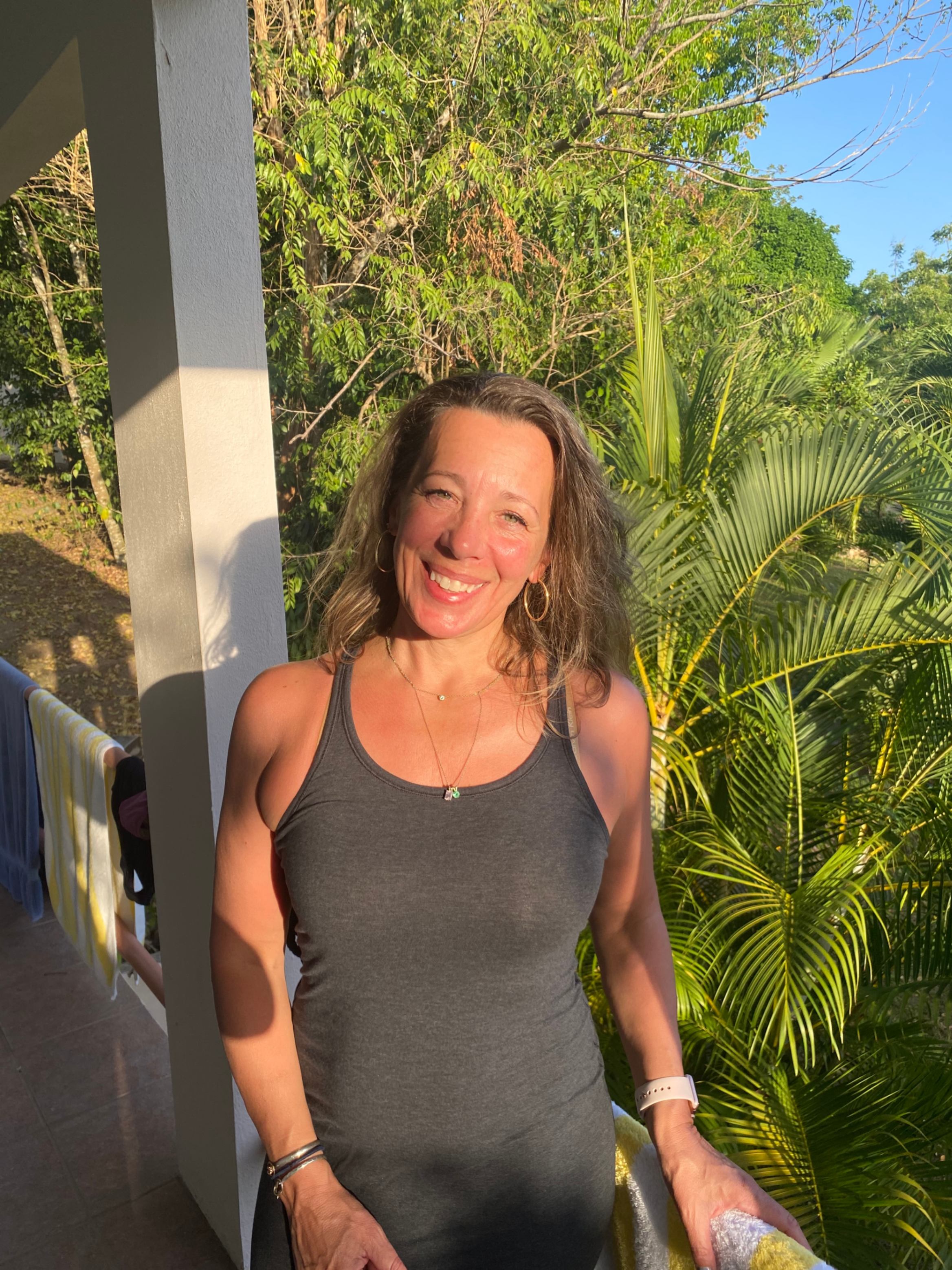 portrait of a woman with a big smile, outside wearing a blue top.