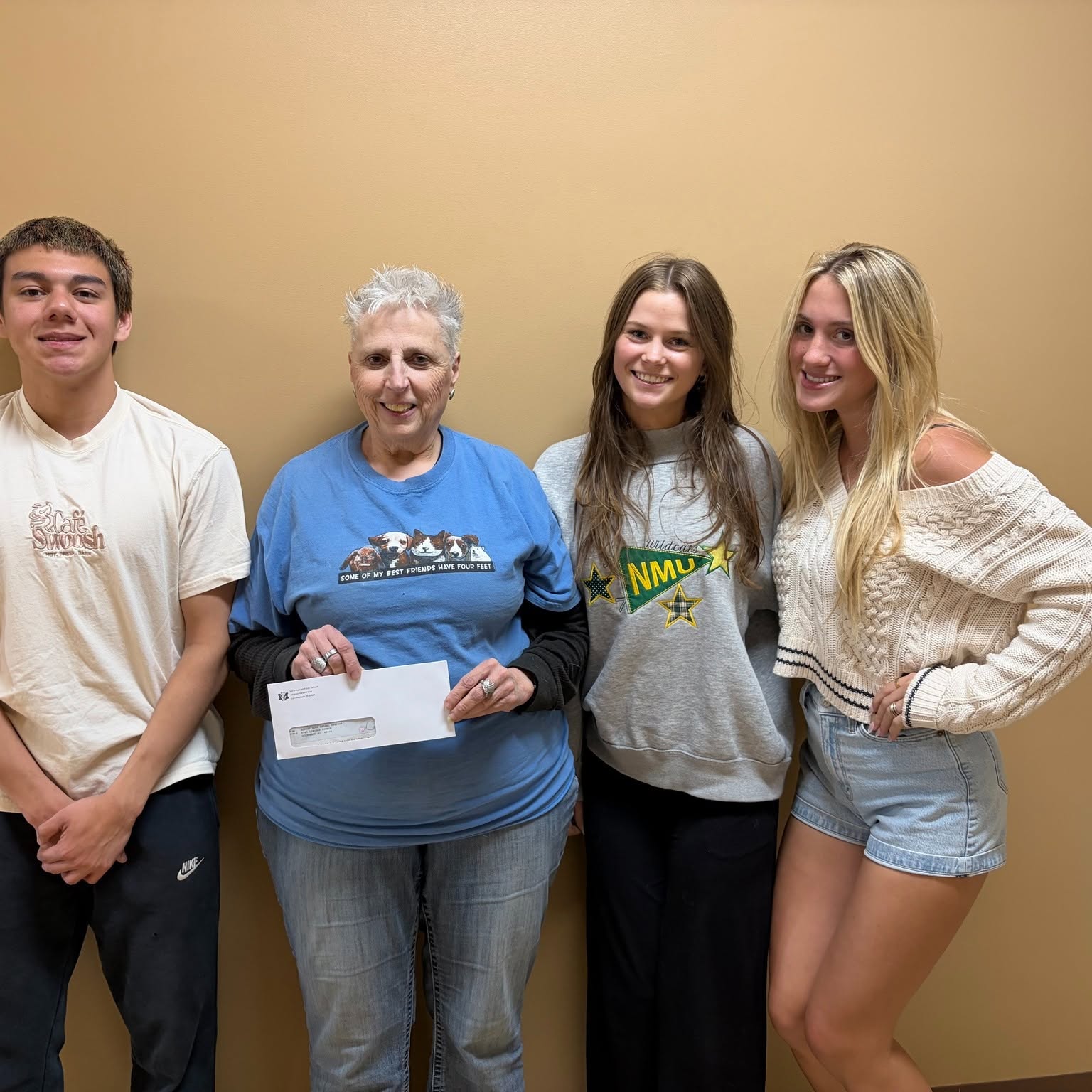 Pictured here is Diane Luczak from AHAS is pictured accepting a check from Di’Angelo Saldana, Lucy Baumgartner and Avea Brown against a plain wall at the Almost Home Animal Shelter.