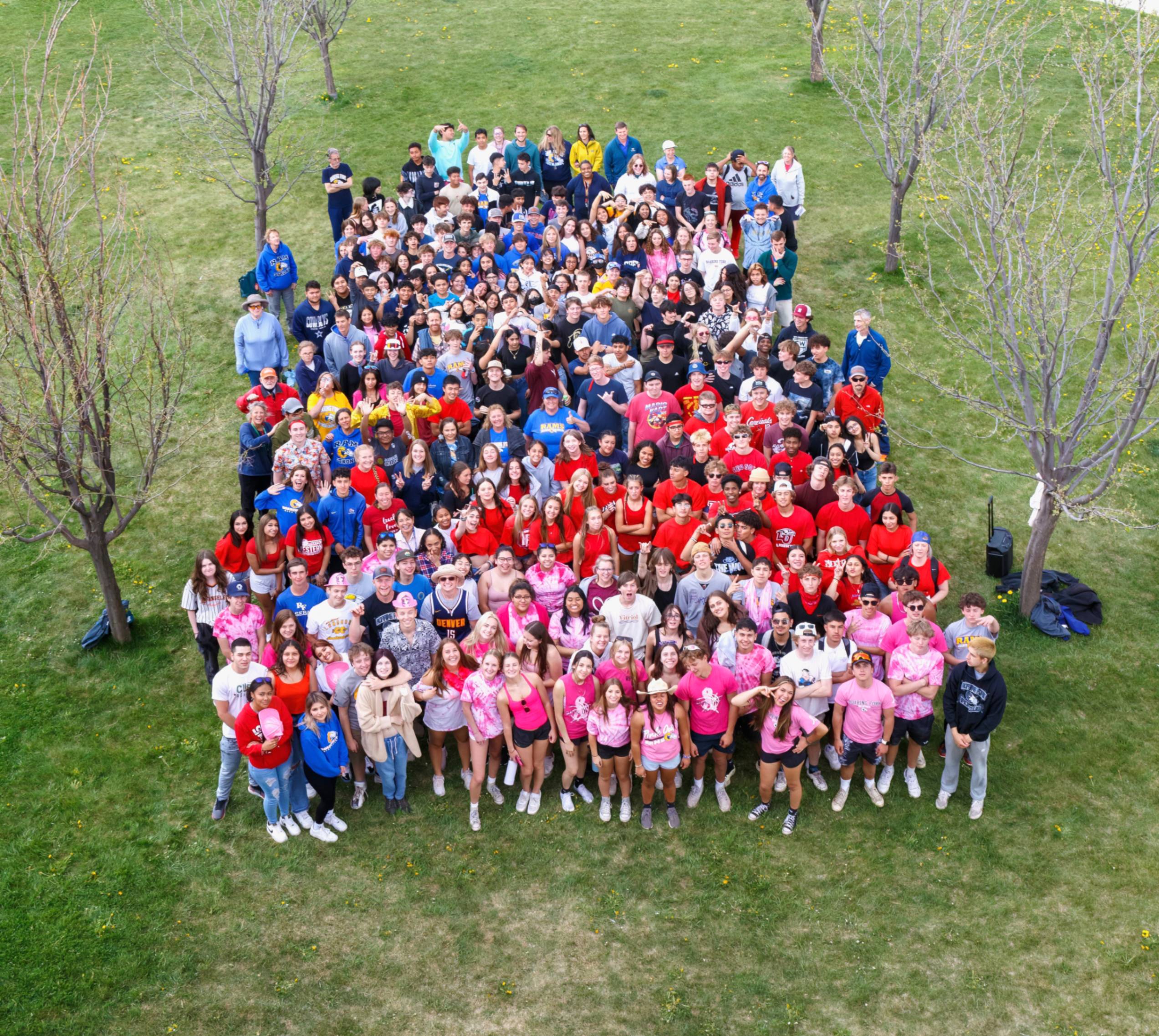 Students in a group outside with classes wearing different colors, taken from a drone above