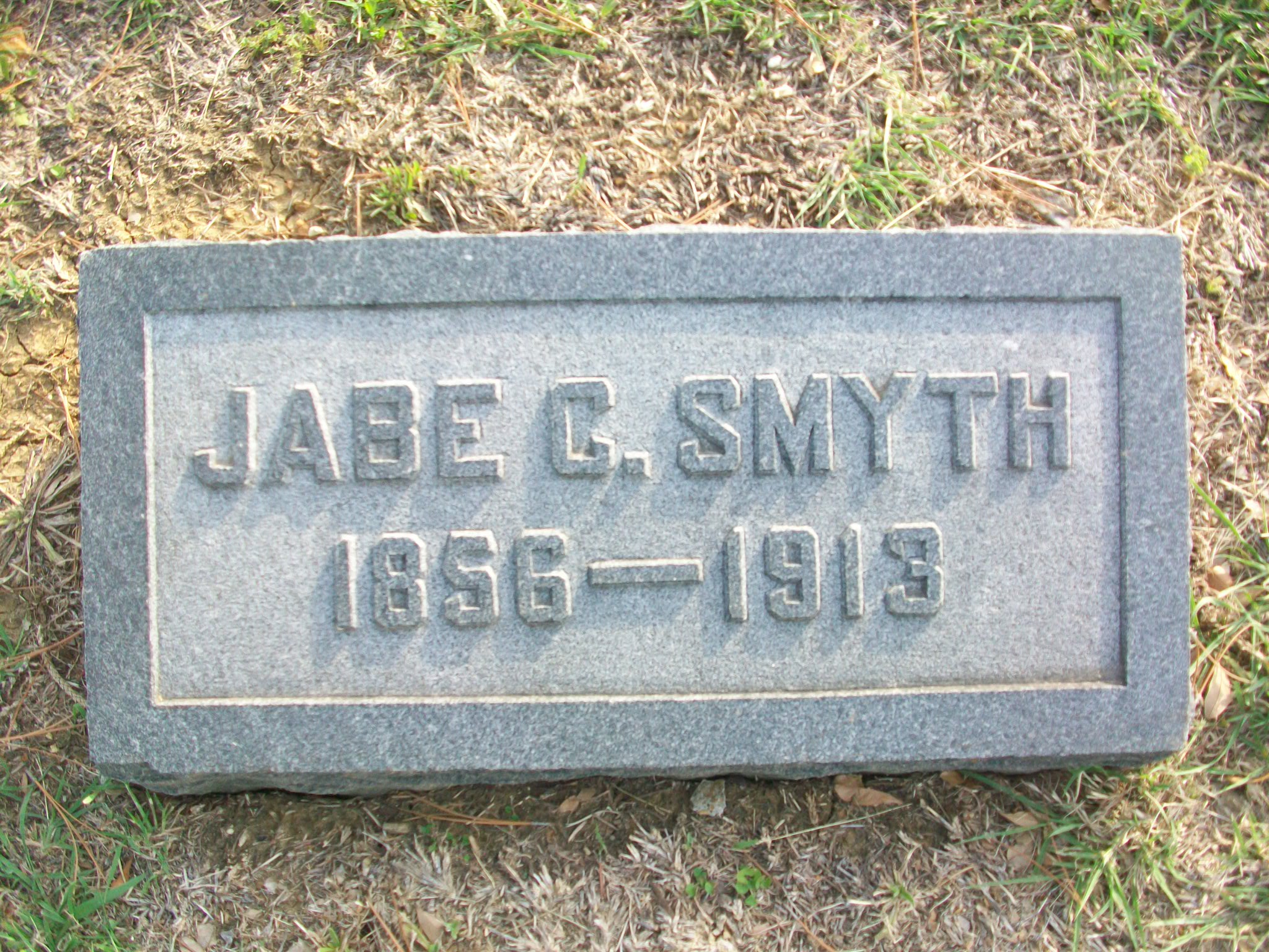Grave marker for Jabe G. Smyth, reading “Jabe G. Smyth, 1836–1913,” surrounded by grass and trees.