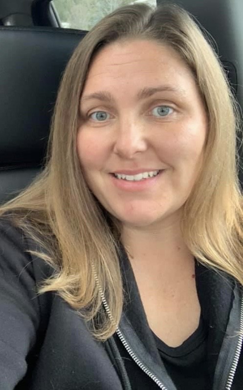 Selfie of a woman sitting in a car, wearing black. 