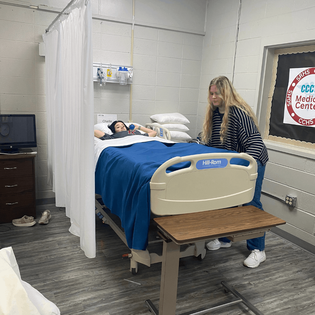 female student adjusting a hospital bed.