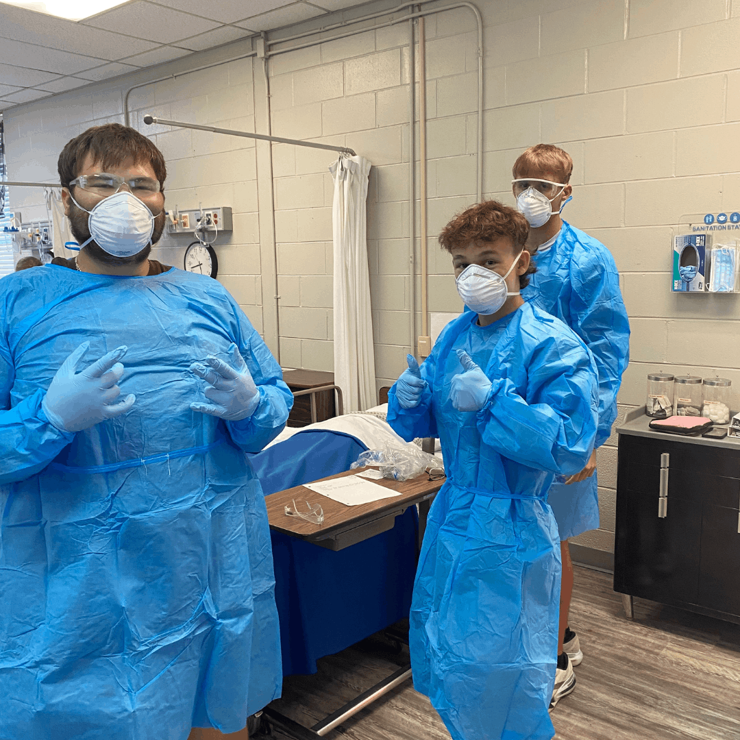 3 male students in PPE giving a thumbs up