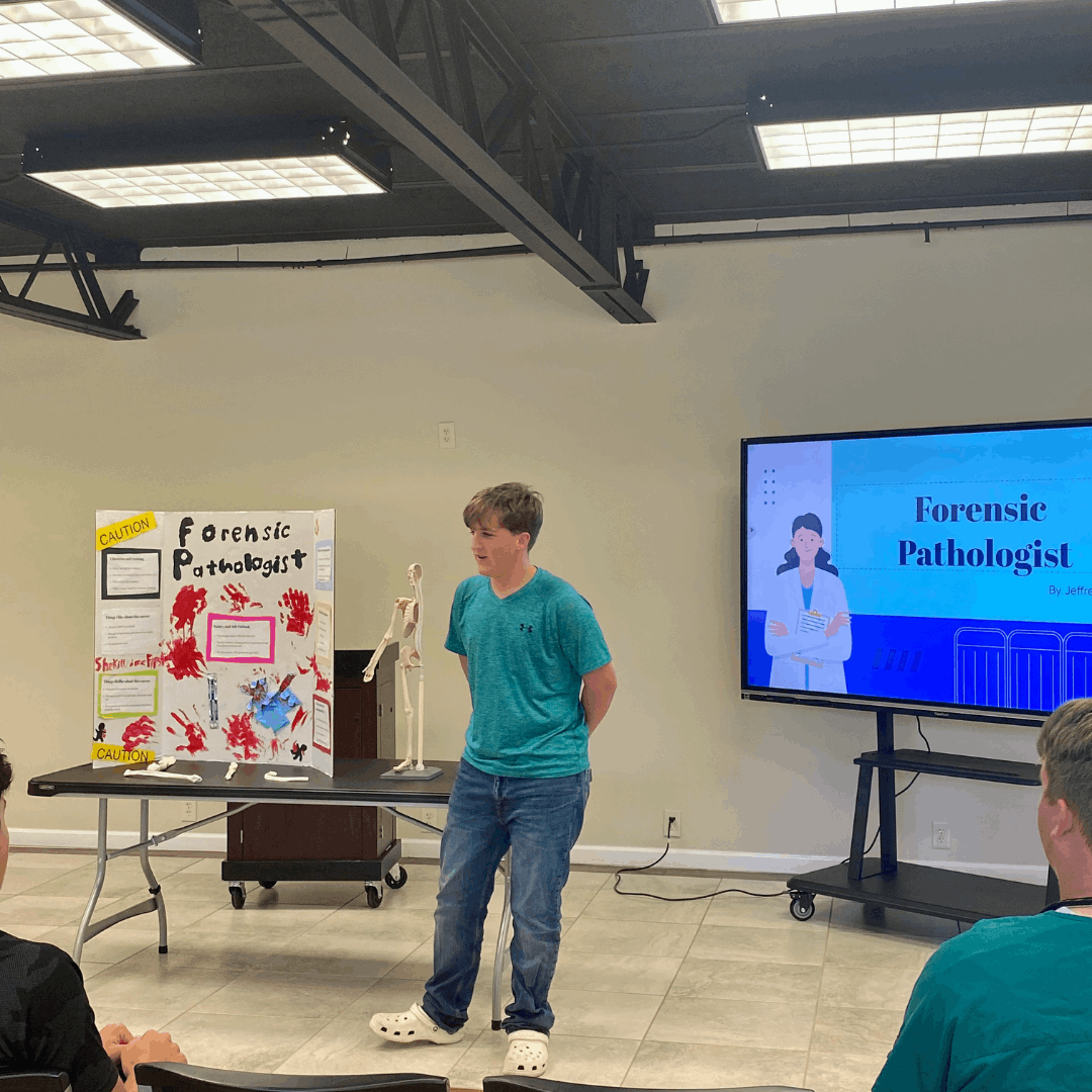 male student presenting forensic pathologist career trifold standing on stage