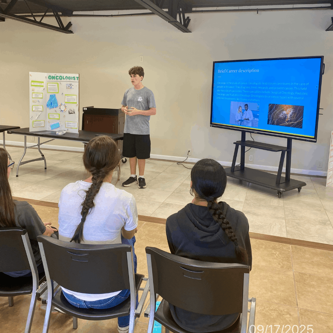 male student standing on stage giving a career presentation