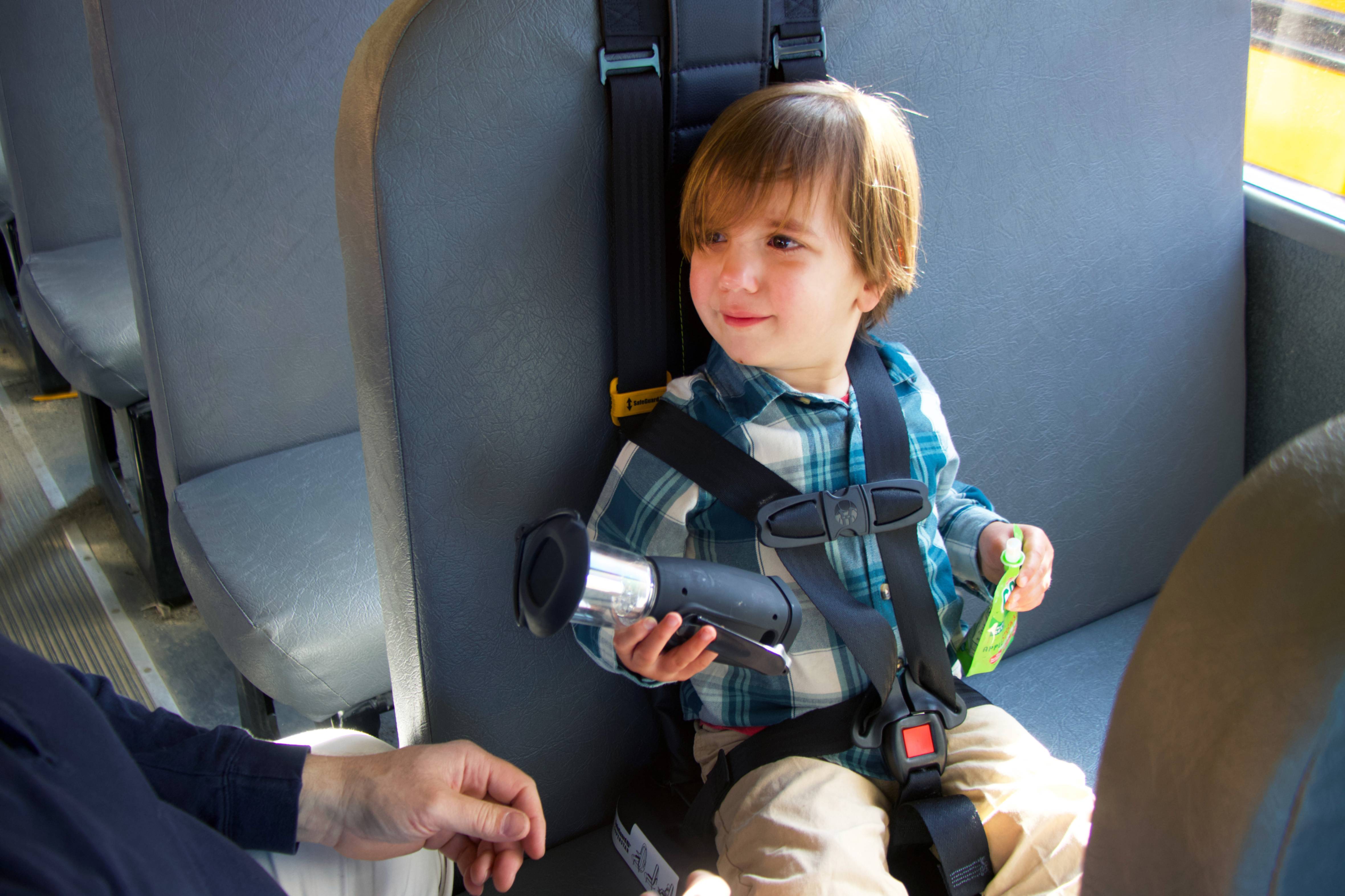 image of preschool student in a 5-point harness on school bus
