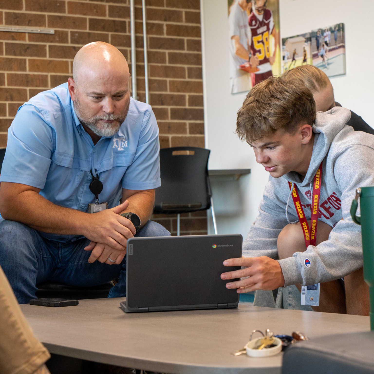 Staff member and students look at a laptop screen